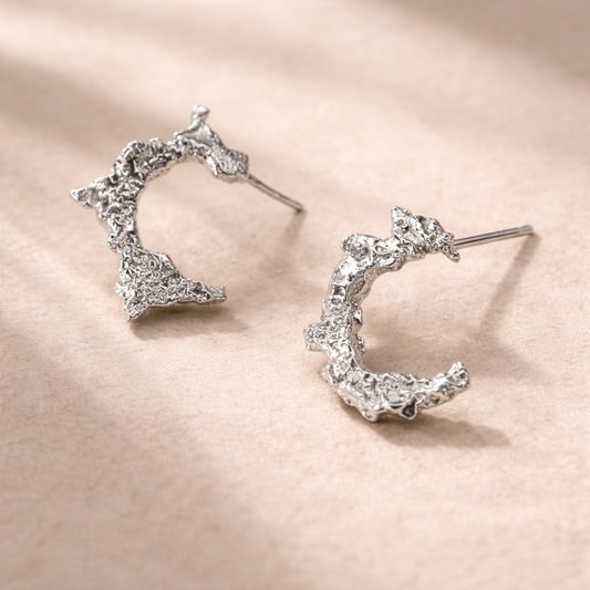 Handmade sterling silver Snow Moon jewellery on cream fabric, organic texture, quietly powerful design